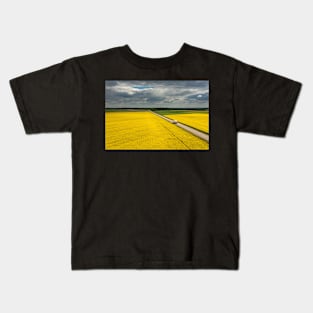 Truck on a road, aerial landscape of a road amongst fields of yellow colza Kids T-Shirt